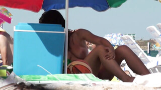 Schattige rondborstige brunette met bruine lijnen en grote borsten op het strand