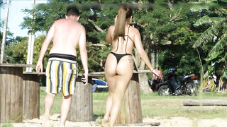 Vrouw met een geweldige dikke kont die string draagt wordt gefilmd op het strand
