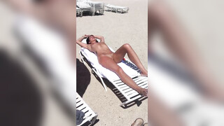 Hete vrouw met mooi lichaam en geschoren kutje is aan het zonnebaden op het strand